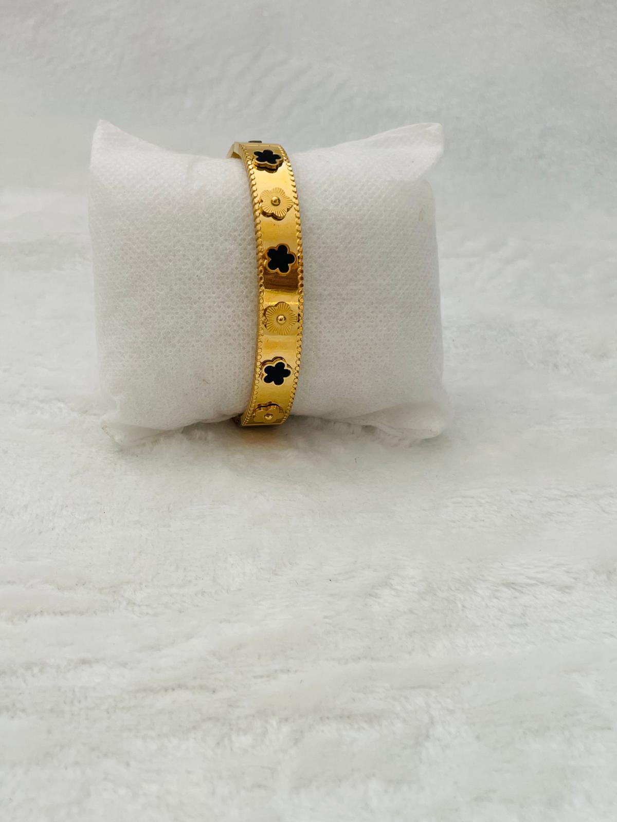 Pulsera dorada con tréboles negros de estilo elegante